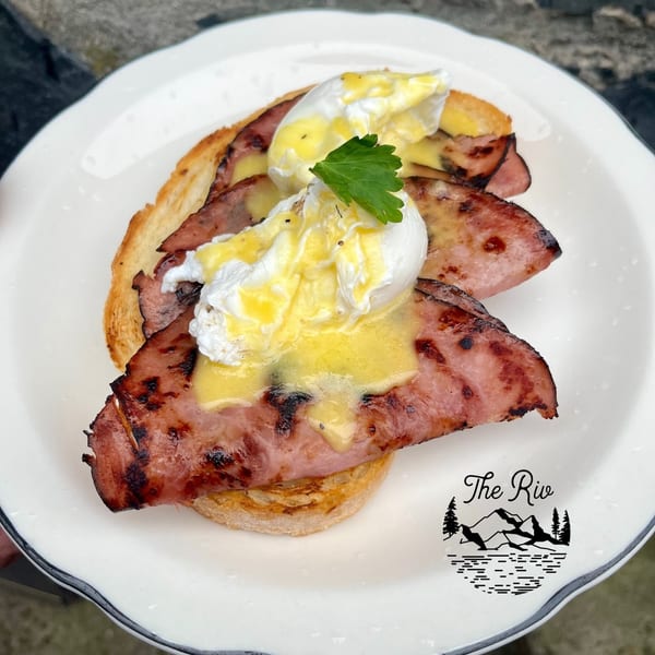 Eggs Benedict with grilled ham, poached eggs, hollandaise sauce, and parsley on toast.